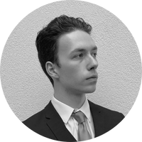 A black and white image depicting a lateral portrait of Andrea Stramondo, a young man around twenty-five with dark, short hair and dark eyes, dressed in a dark three pieces suit and a bright tie, above a bright-colored background.